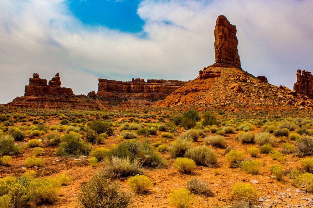 a hoodoo stands in front of a craggy mountain range in Bears Ears national monument