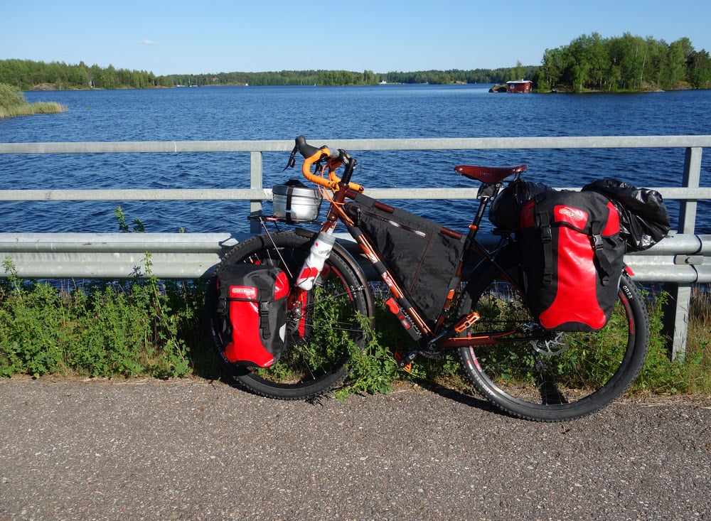 a bikepacking rig on a bike with saddlebags on a bike path in front of a lake