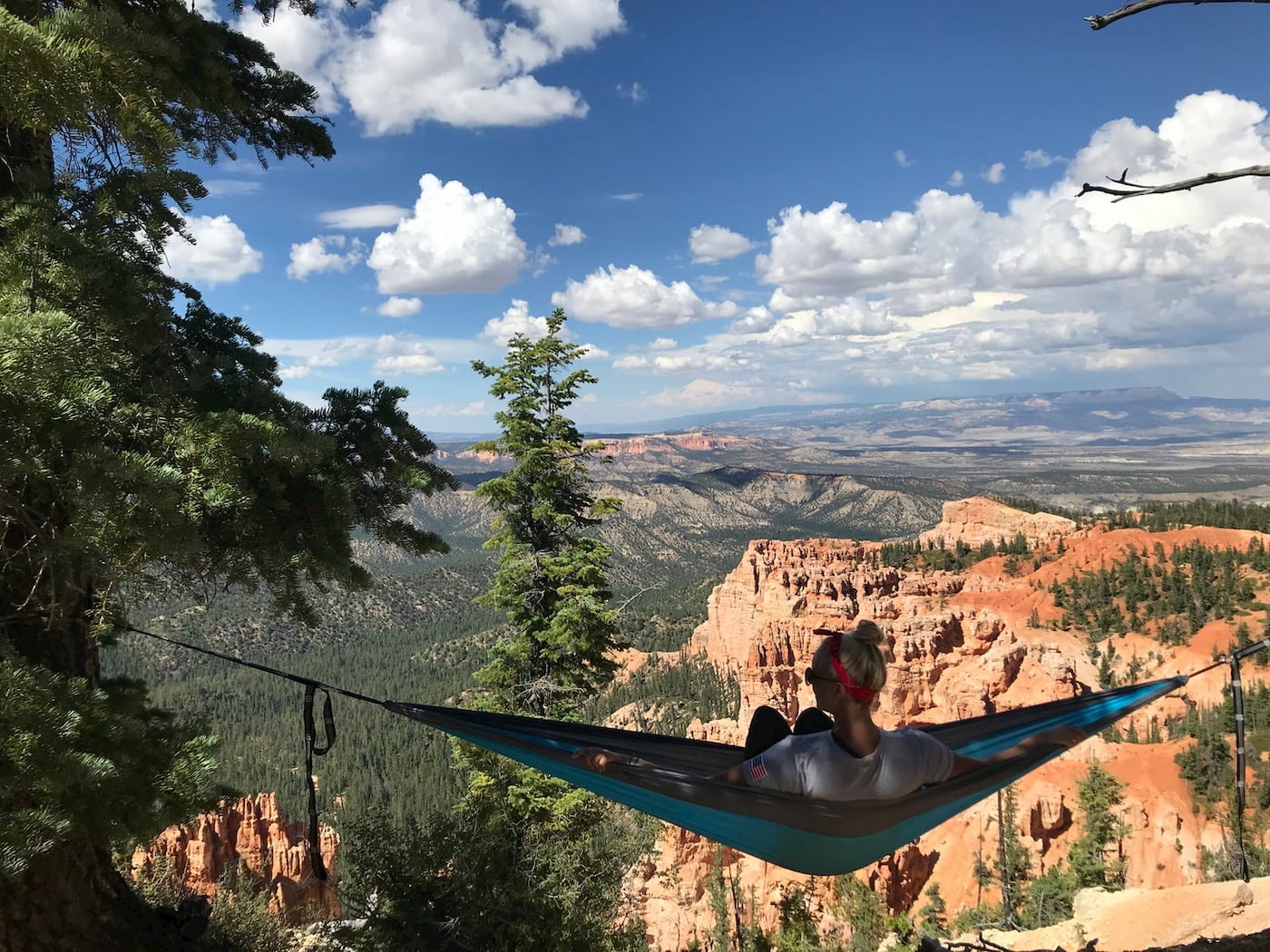 Girl hanging in hammock over sunset canyon.