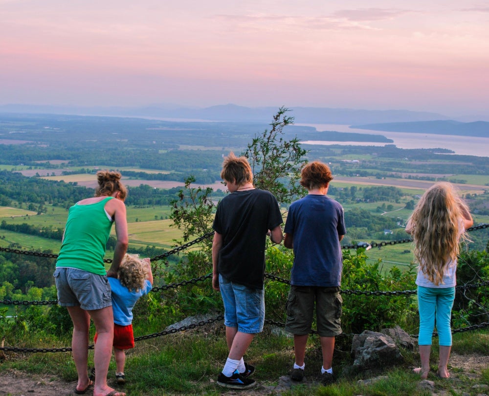 Mother and four children look over valley in Vermont at sunset 