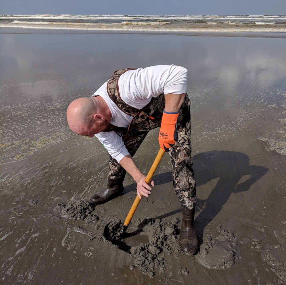 a man digging with a shovel on a beach in washington