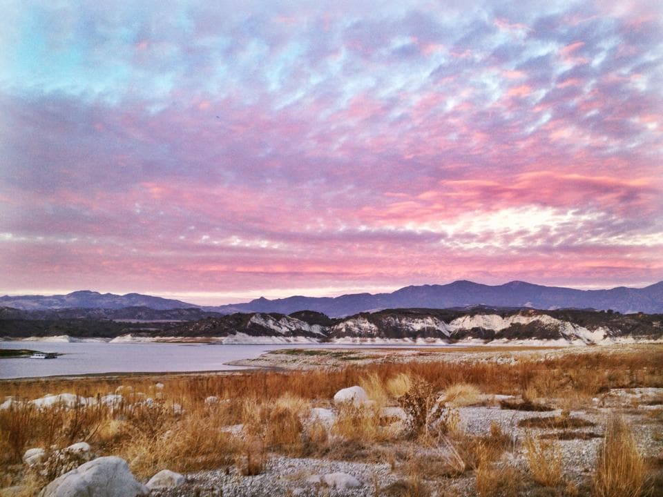 pink sunset over small california lake with mountains in the background