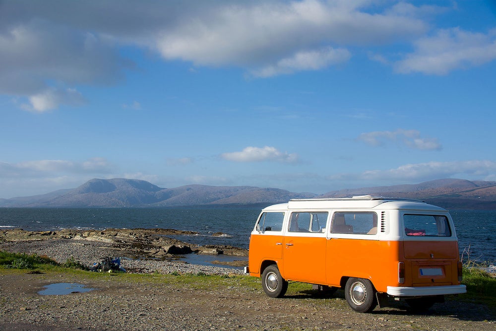 a volkswagon camper van parked on the shore of the ocean