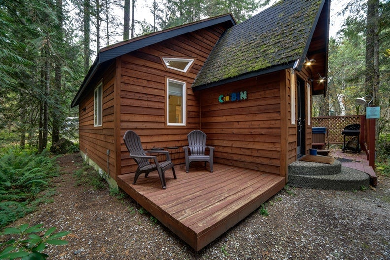 the outside of a mt. baker cabin with adirondack chairs surrounded by trees