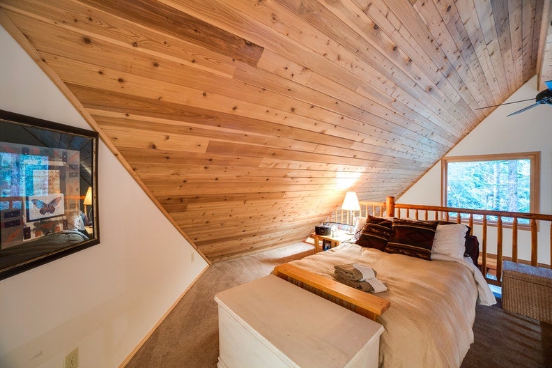 a lofted bedroom with a large TV and wooden walls in the mt. baker cabins