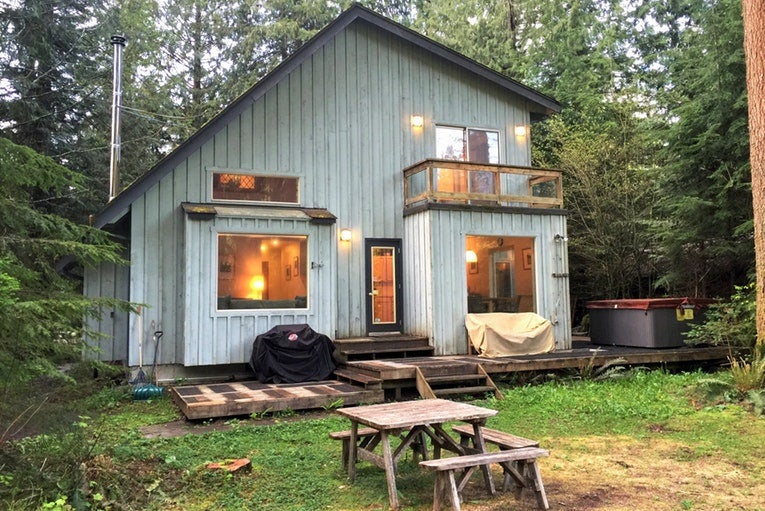 a two-story cabin with large windows and a picnic table outside