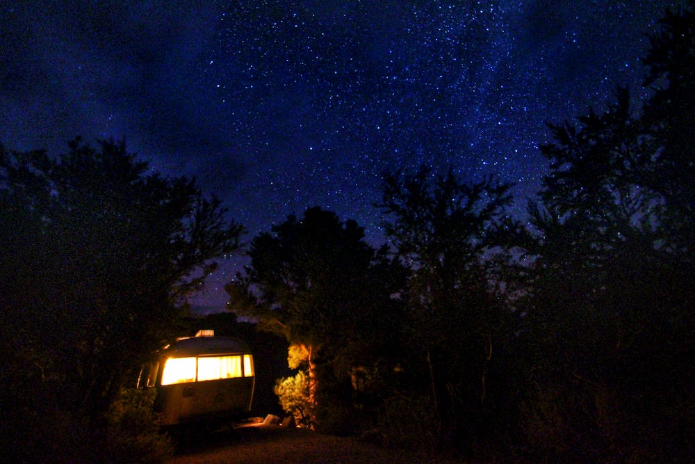 Airstream with light on and dark, starry sky in background 