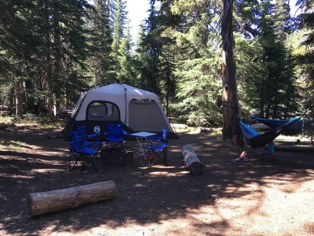 a fully assembled campground with a tent, camping table and fire pit in crater lake national park