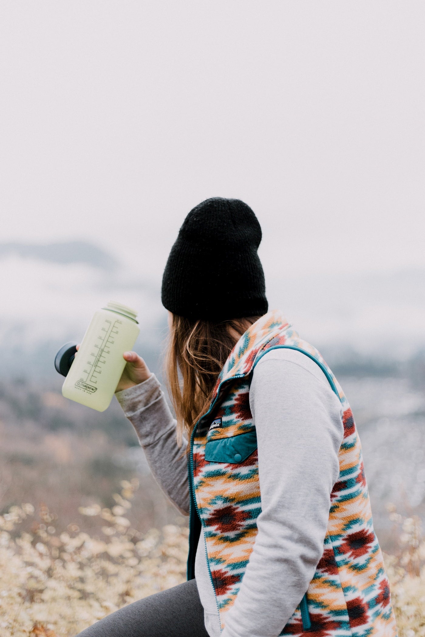 Women wearing outdoors brands in layers and drinking water out of a nalgene.