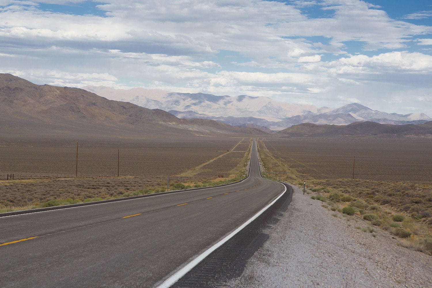 a stretch of Route 50, cutting through featureless, brown landscape with mountains in the distance. 