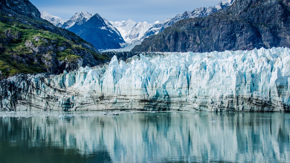 Glacier along the water in the foreground with mountains in the background.