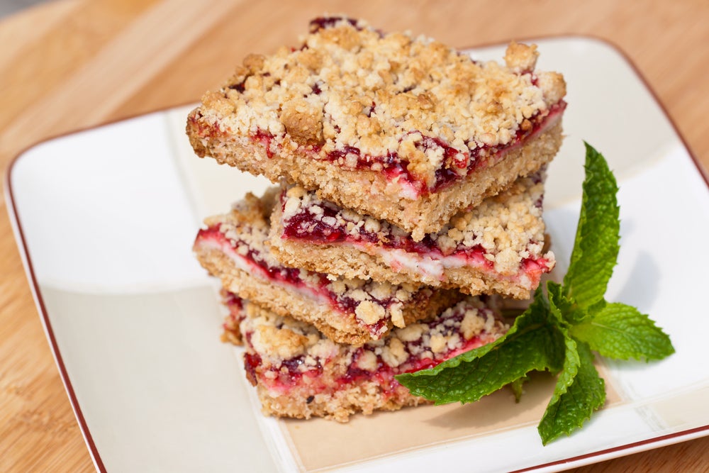 Raspberry bars stacked on one another with mint on plate 
