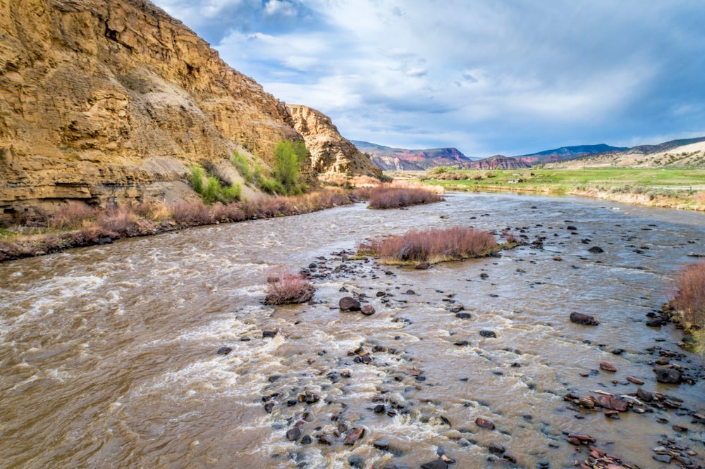 Wide point in Upper Colorado River dotted with river rocks among rapids.