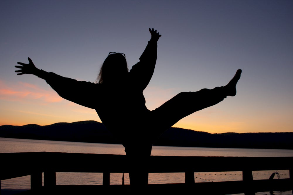 a woman's sillhouete posing for a photo in front of a lake