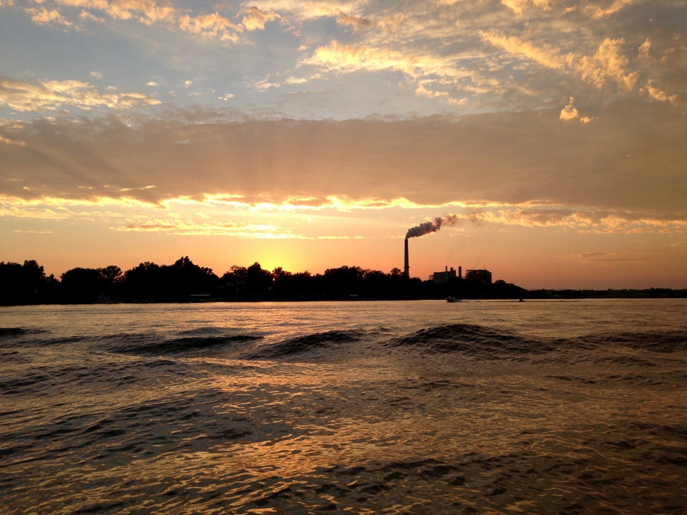 Lake of Egypt at sunset with buildings and factory stack in background.