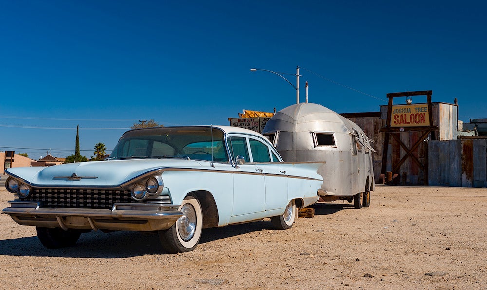 a vintage car towing an airstream trailer in the desert