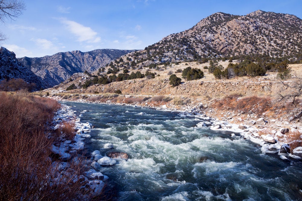 Light dusting of snow borders the shores of the rushing Arkansas River.