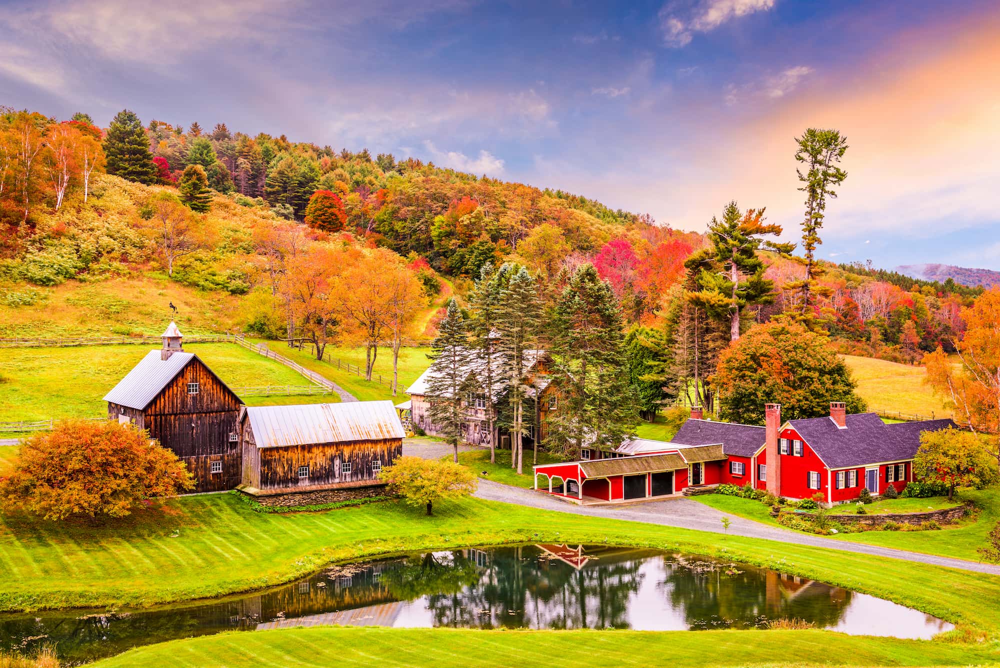 Panoramic view of red barn and old house with colorful trees in background