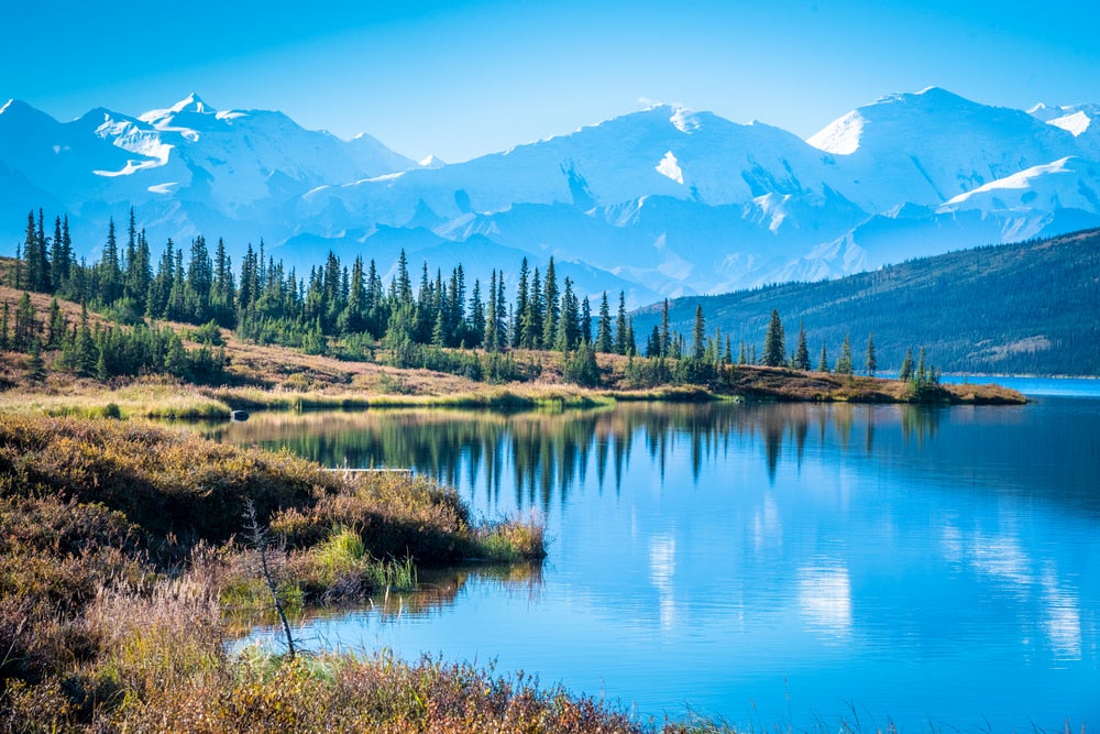 Snow capped Denali mountain range with a lake in the foreground.