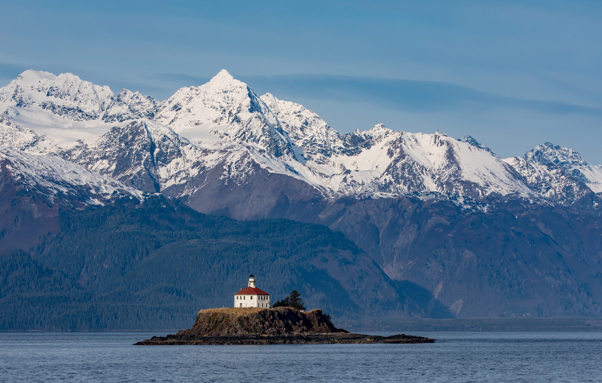 Panoramic view of snow-capped mountains and island with lighthouse on island