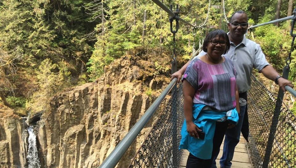 Myrna and Sheldon standing on a bridge over a gorge with a waterfall in the background