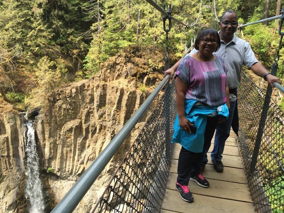 Myrna and Sheldon standing on a bridge over a gorge with a waterfall in the background