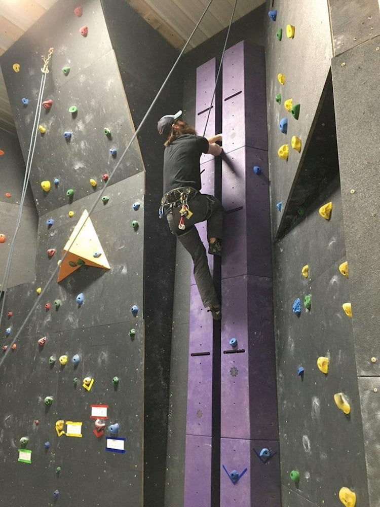 a man climbs a wall crack in a climbing gym
