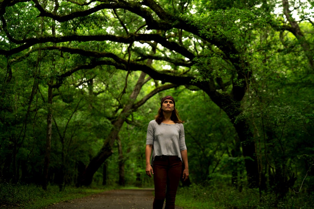 a woman stands on a tree lined hiking trail