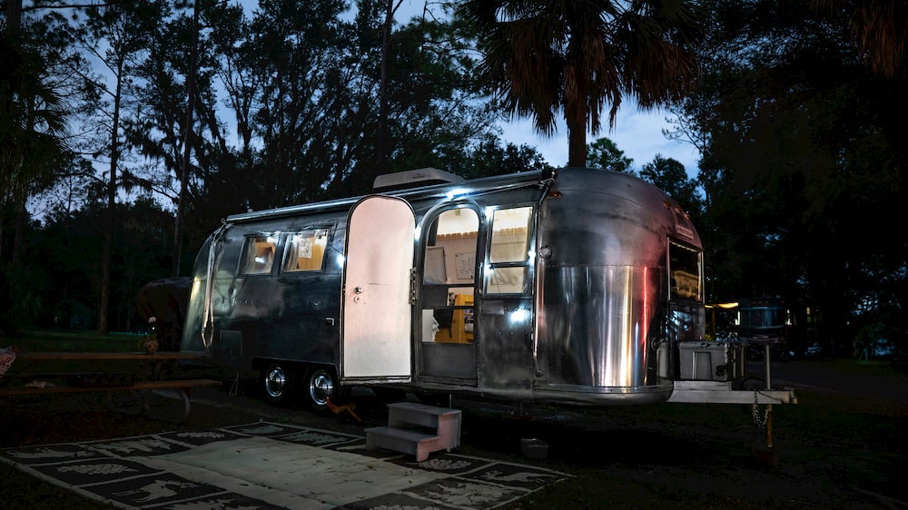 An open airstream RV parked at night in a campground