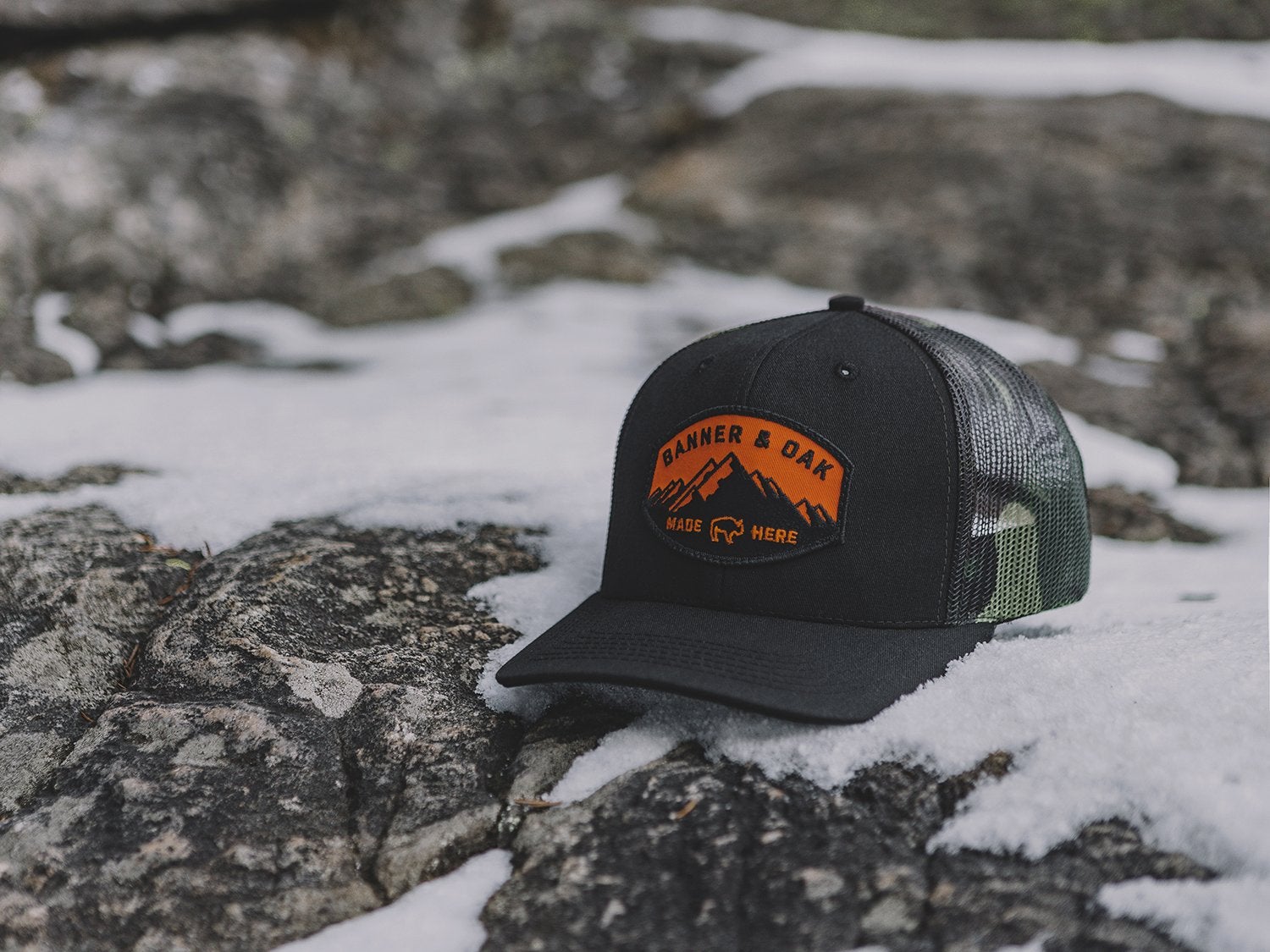 a trucker hat rests on a snowy field