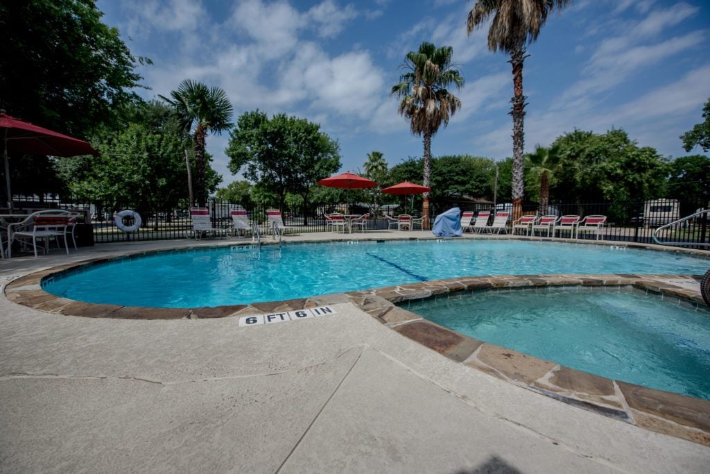 a pool surrounded by chairs and palm trees