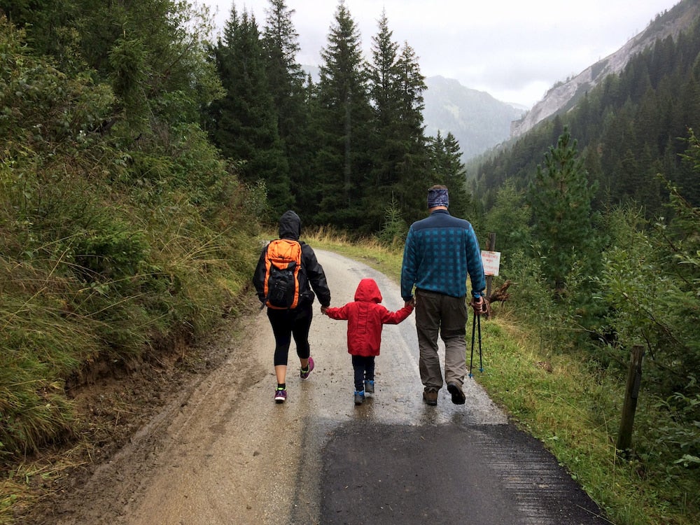 Family of 3 walking on a path with mountains in the background 
