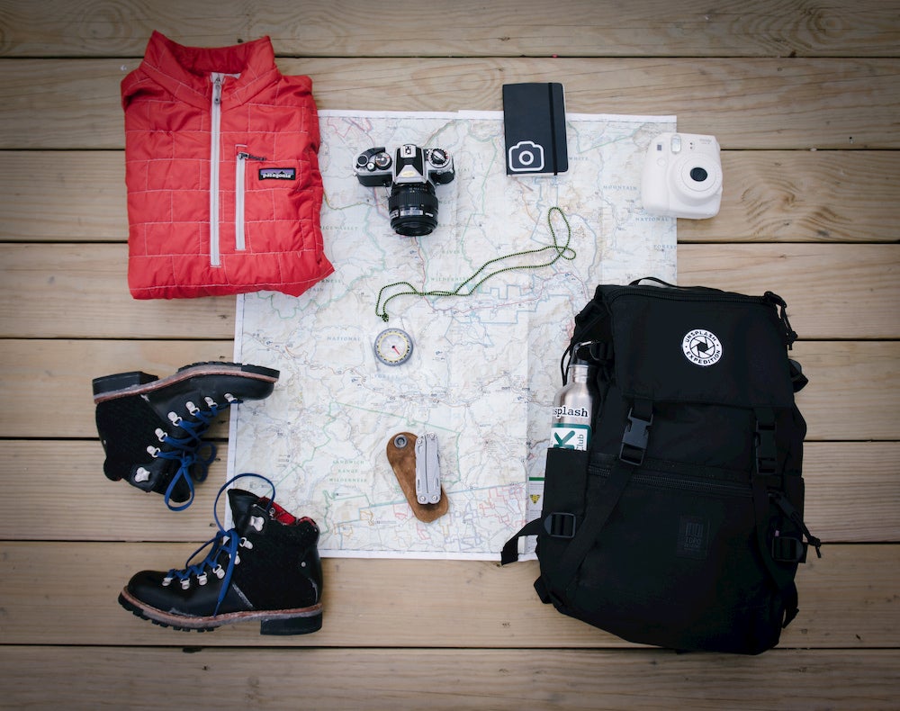 Day hiking gear laying flat atop map on wooden deck. 