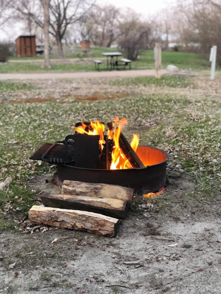 a pile of logs near a fire pit at a campsite