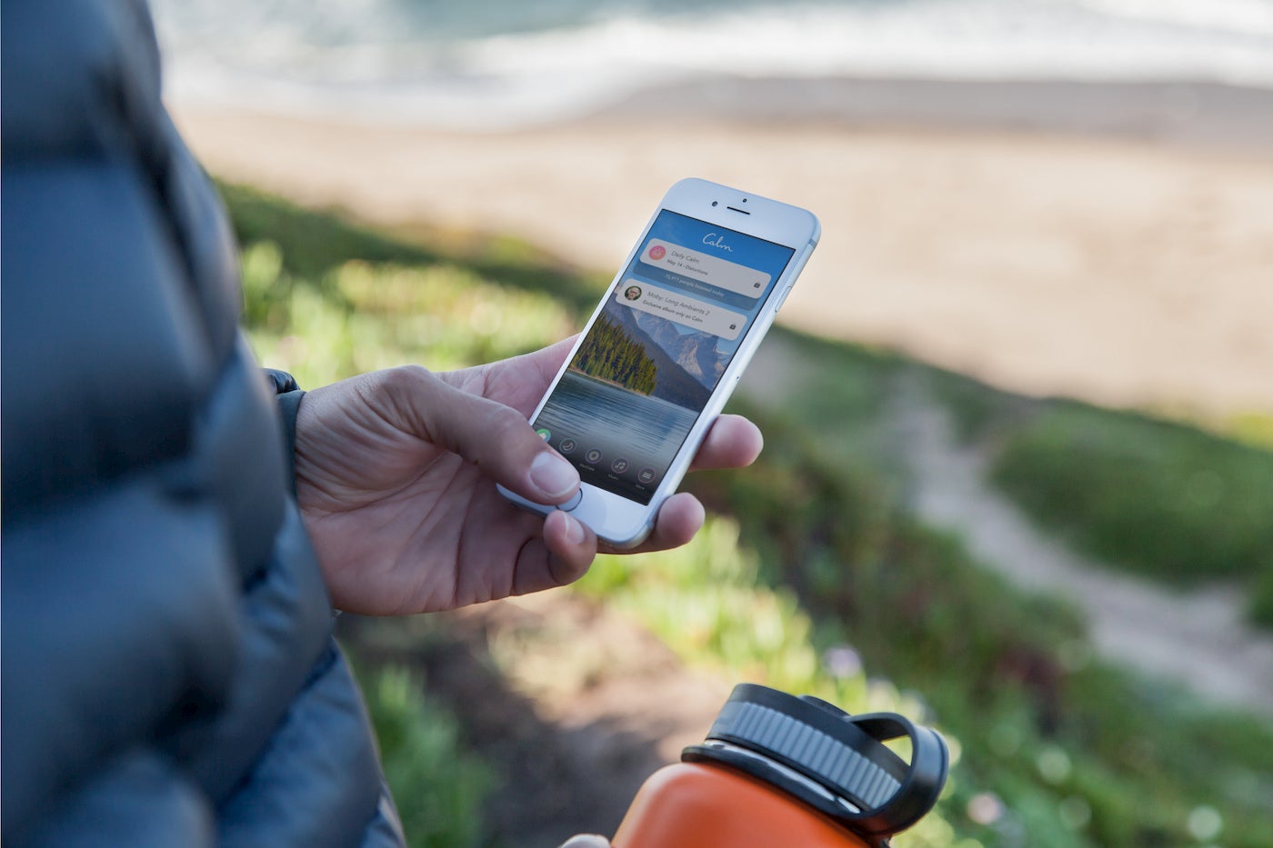 Person holding water bottle and smart phone, using the 'Calm' app