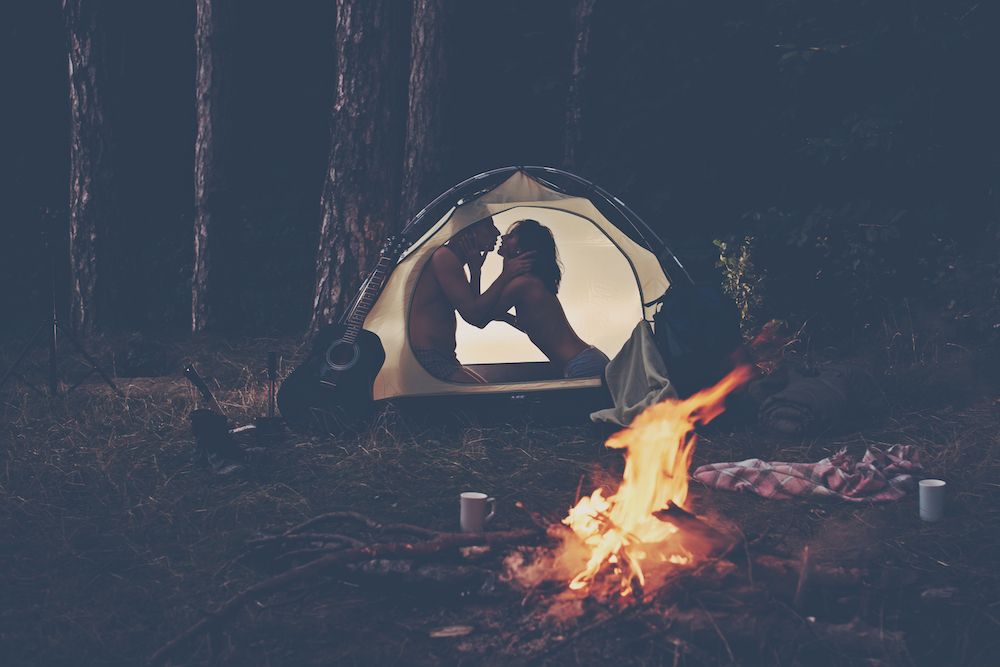 silhouette of naked man and woman having camping sex in an illuminated tent at night