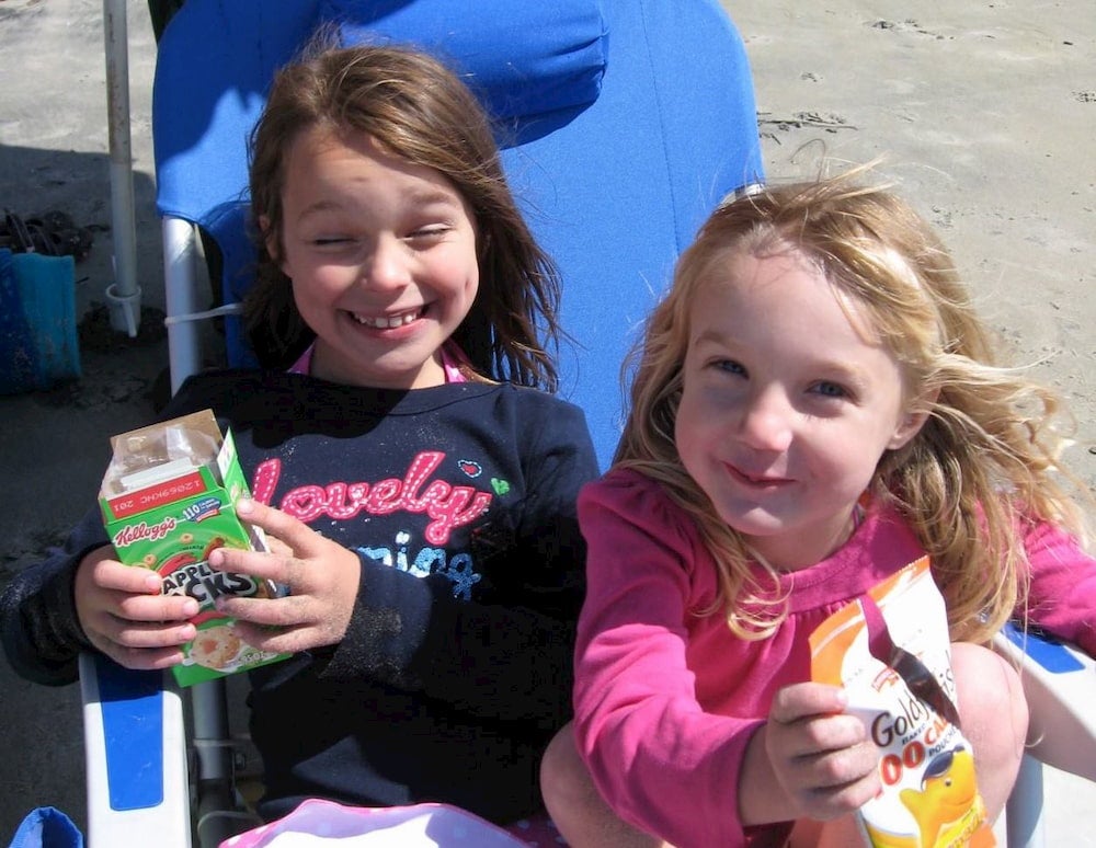 Two girls smiling and eating snacks