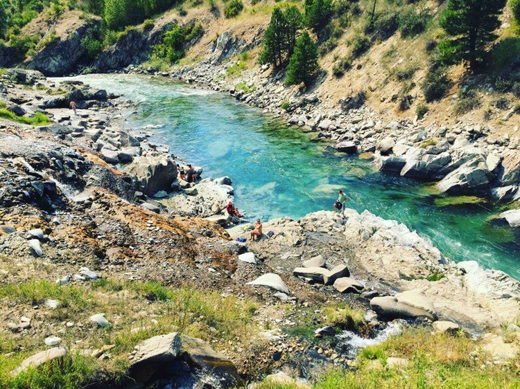 people stand along the edge of a clear blue river in idaho