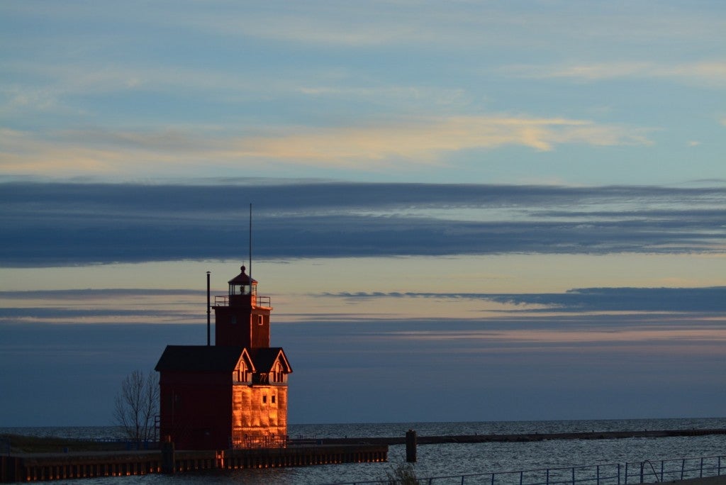 a stocky red lighthouse on a pier into lake michigan