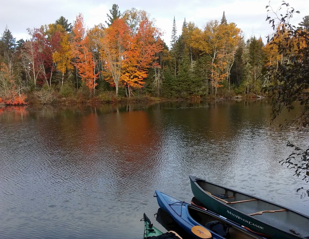 Canoes on a lake with fall trees in background 