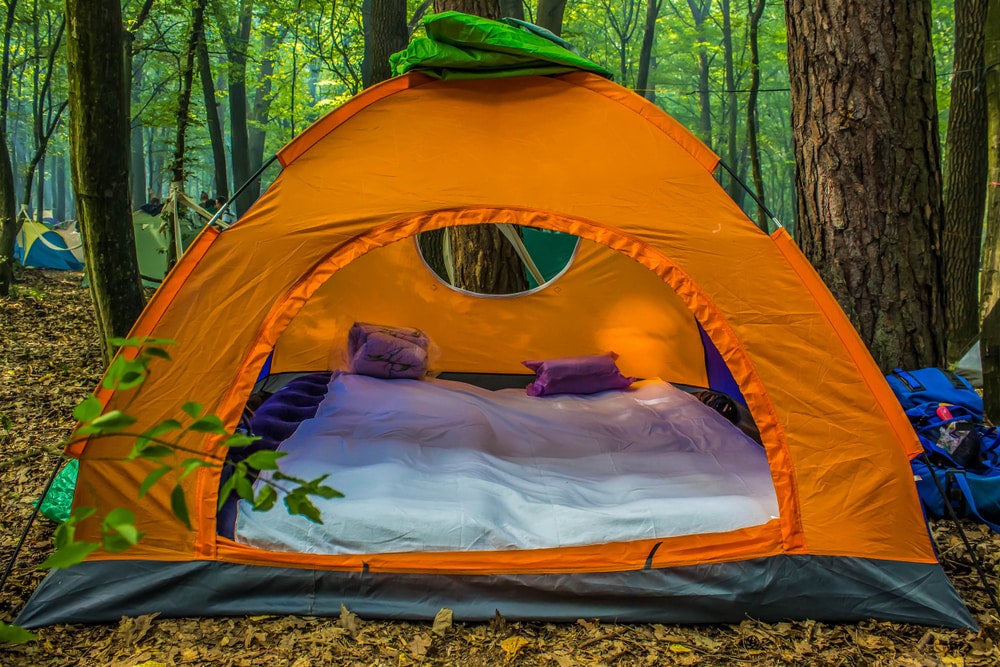 a tent in the woods with a mattress set up inside it