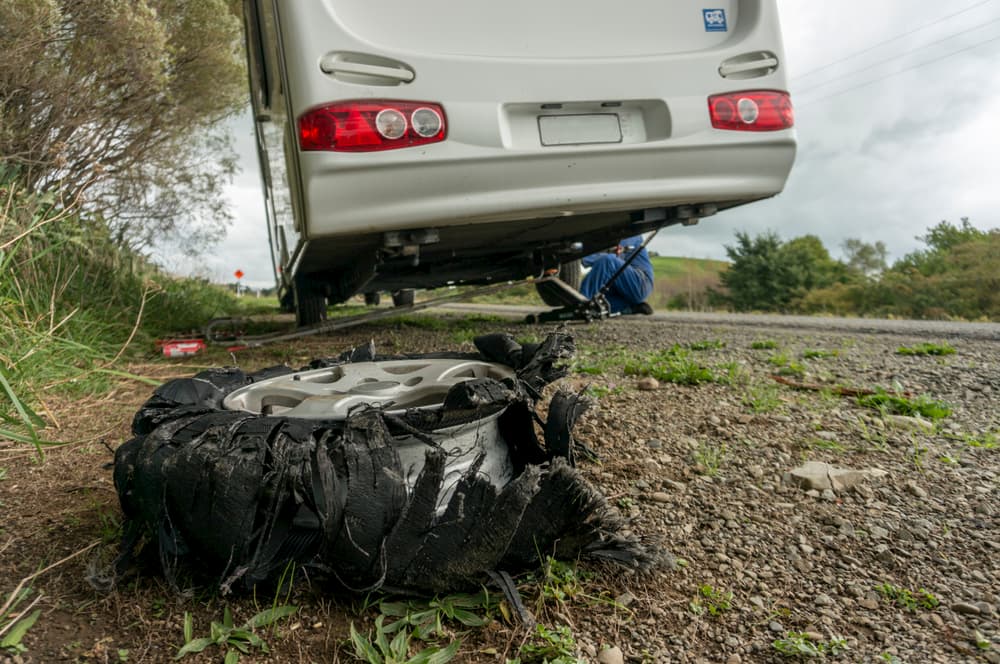 a man fixing an RV camper next to a broken tire