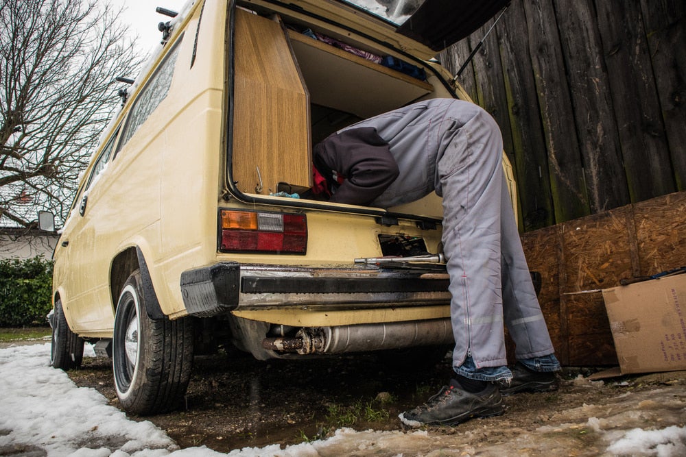 a man reaching into an RV van to repair the vehicle