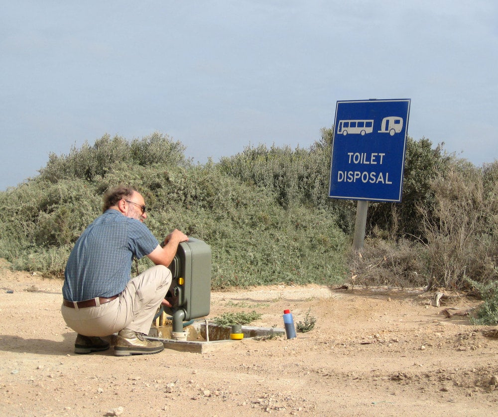 a man dumping a black water tank at a rest stop