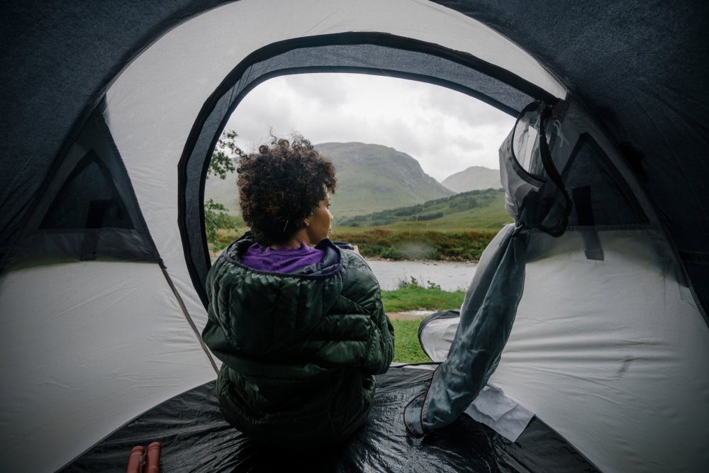 a woman sitting in a tent while it rains