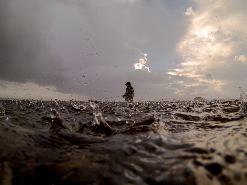 Fly fisherman in puget sound during a rain storm.