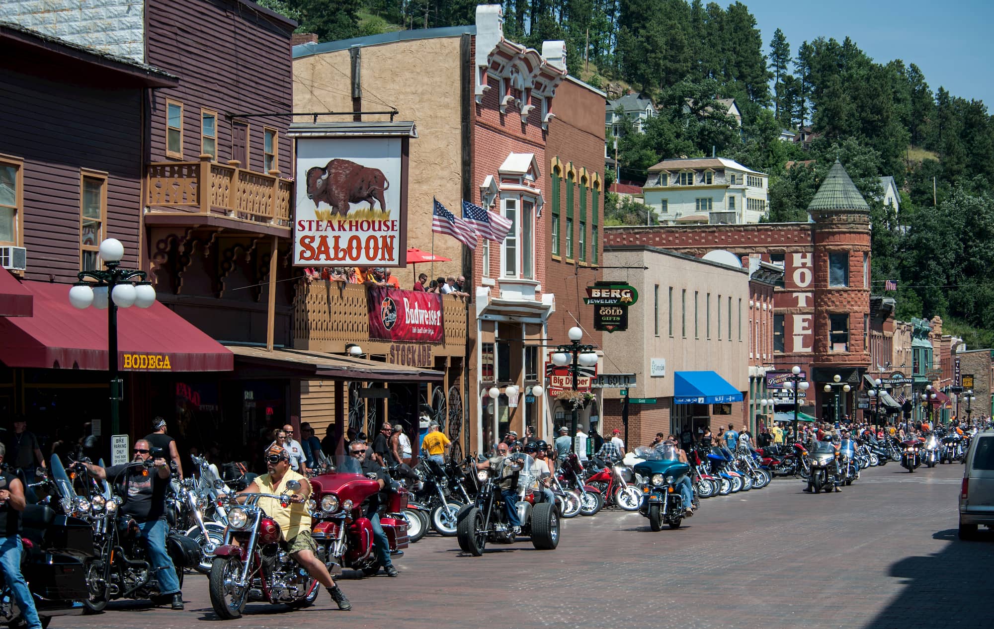 People on motorcycles next to buildings during sturgis motorcycle rally
