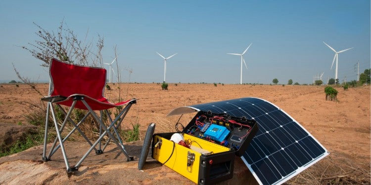 a chair next to a solar generator in a desert near wind turbines