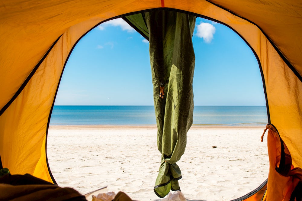 Tent on a beach beside the ocean.