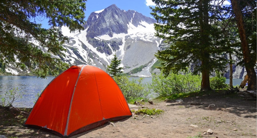 a red tent set up neat a lake with a mountain in the background in colorado